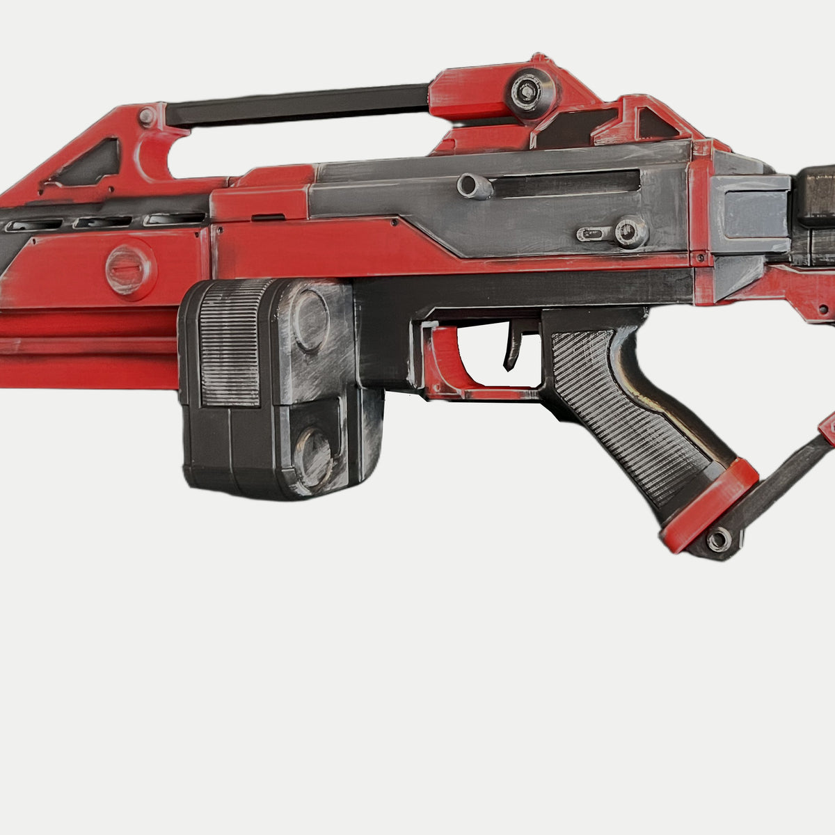 Close-up of the squared black twin magazine below the red and gray AR-70 Raptor Nod receiver, with the ribbed pistol grip alongside it.