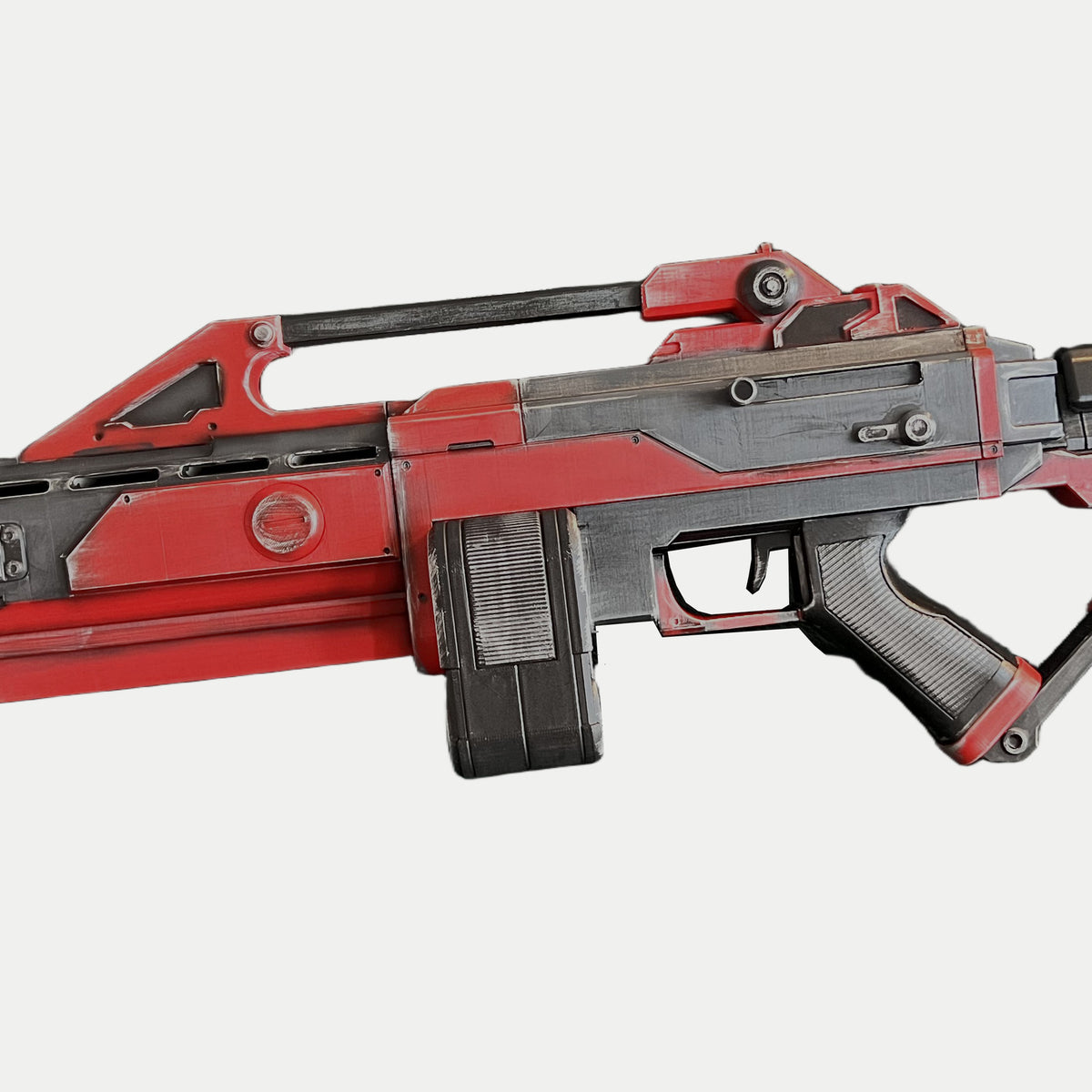 Close-up of the long carry handle and round rear sight on the AR-70 Raptor Nod prop, with red supports and worn gray edges.