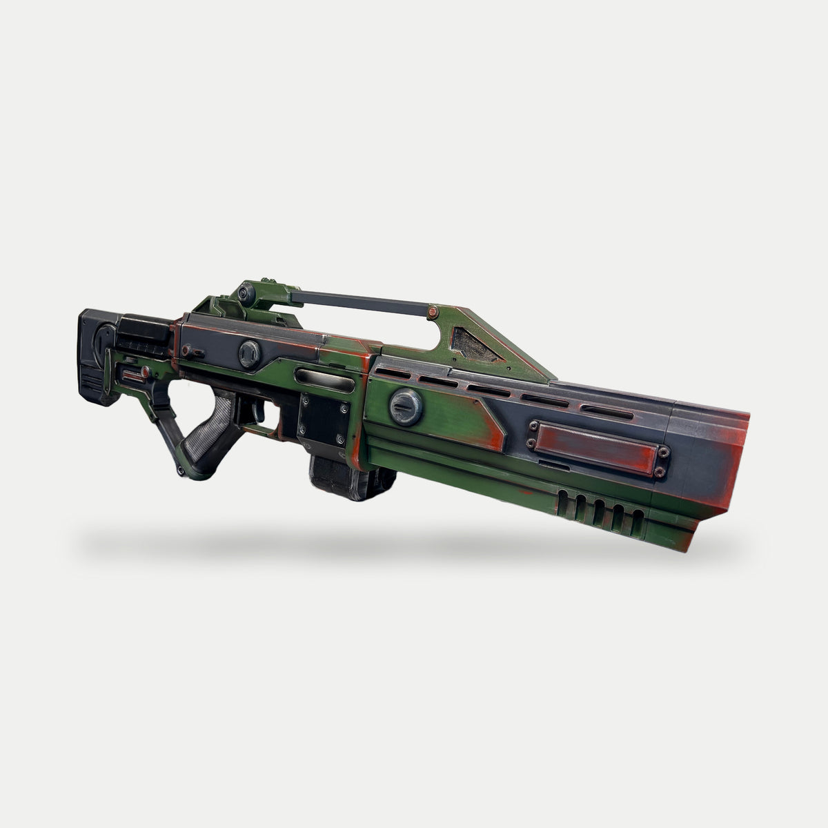 Painted Command & Conquer AR-70 Raptor prop in an angled view, with olive panels, a black drum magazine and the muzzle facing right.