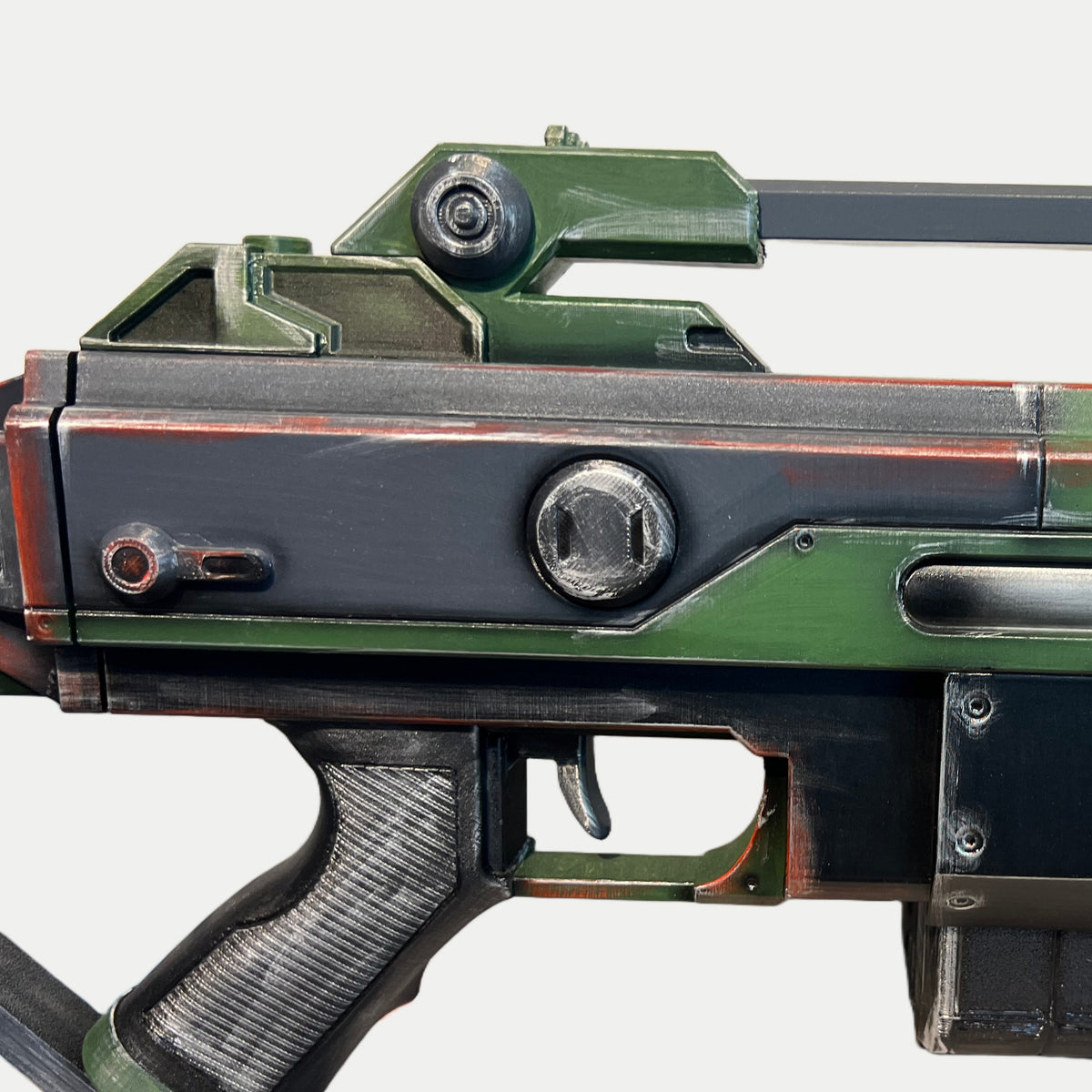 Round receiver knob, small lever and carry handle on the olive-green AR-70 Raptor prop, with silver wear along the edges.
