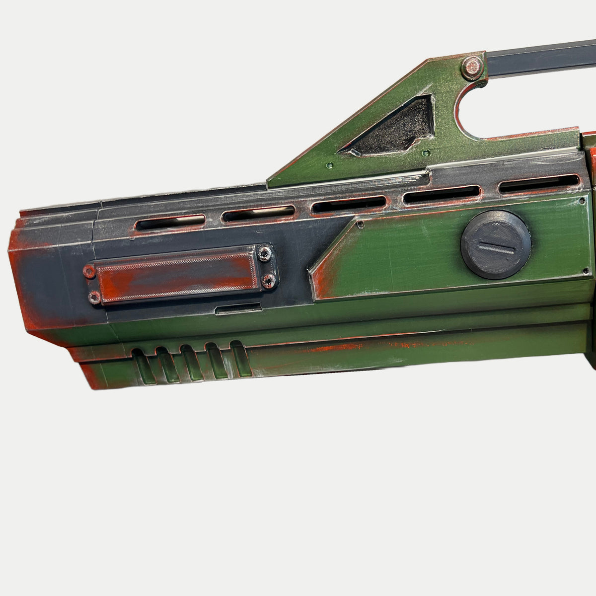 Olive fore-end of the AR-70 Raptor prop with vent slots, a red plate held by four screws and worn silver edges.