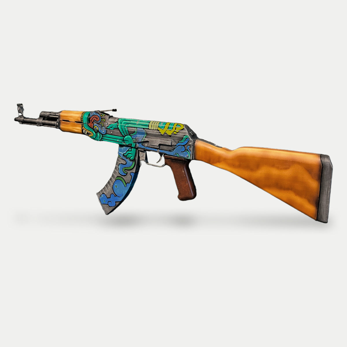 AK-47 Fire Serpent prop at a three-quarter angle, muzzle left, with the orange-brown stock, red-brown grip and painted curved magazine visible.