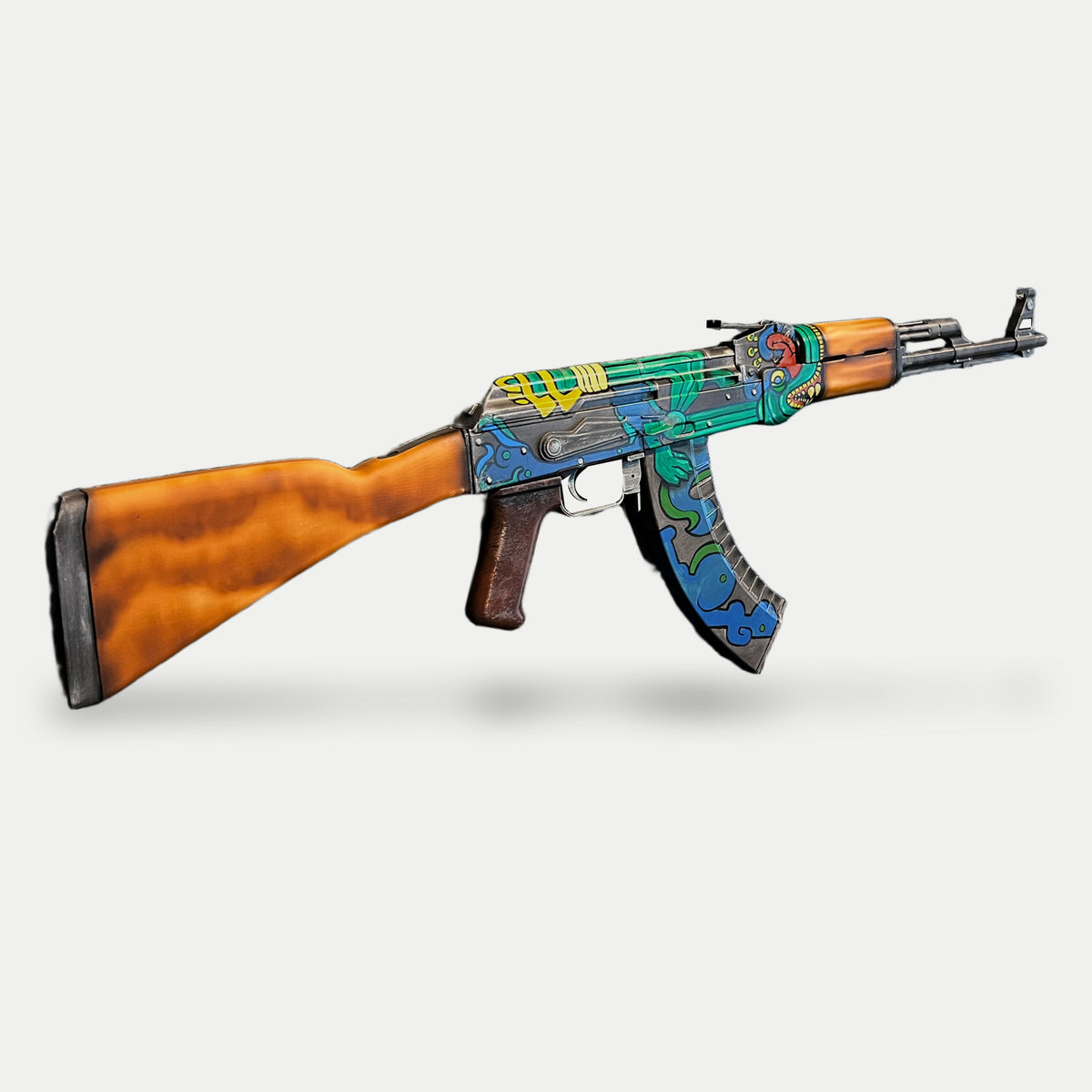 AK-47 Fire Serpent prop from the reverse three-quarter angle, muzzle right, showing the wood-look stock, serpent artwork and blue cloud magazine.
