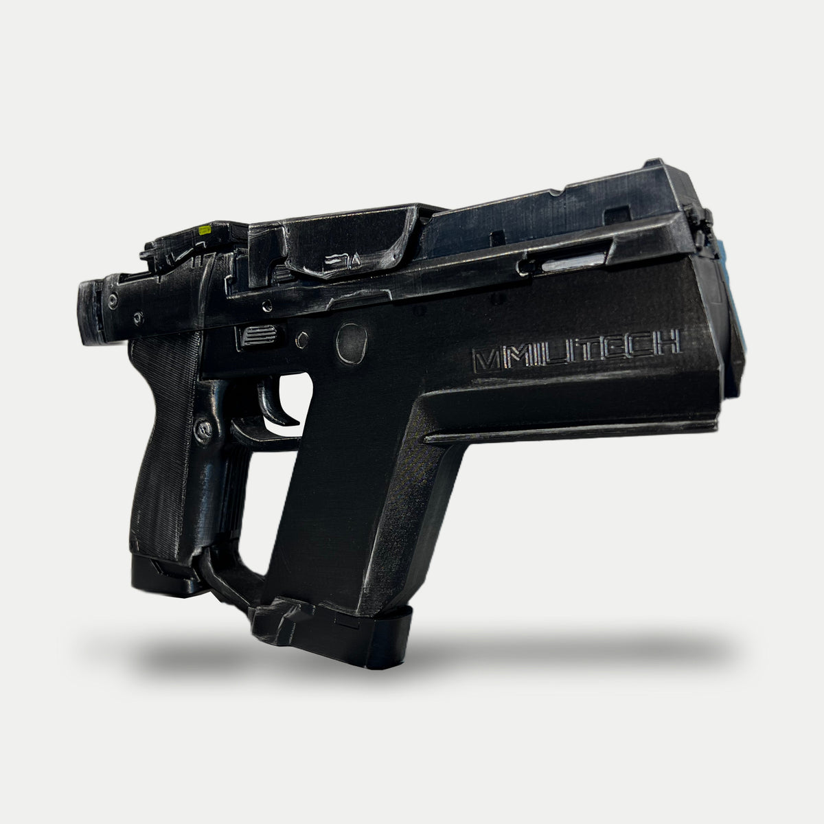 Angled view of the painted Cyberpunk Pariah pistol prop with raised MILITECH lettering, a squared front, open lower frame and black finish with silver-worn edges.