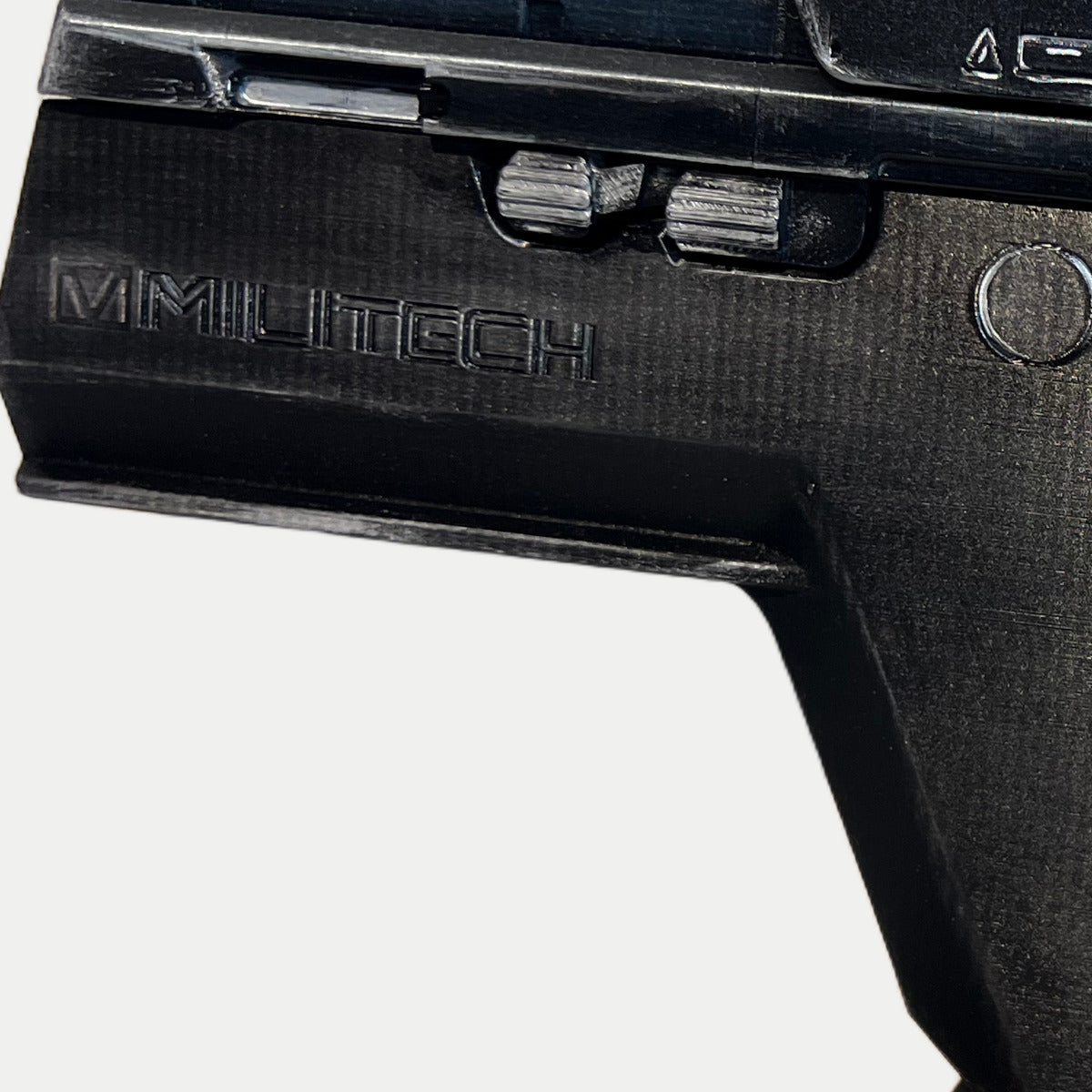 Close-up of the raised MILITECH lettering and ribbed side controls on the black-and-silver painted Cyberpunk Pariah pistol prop.