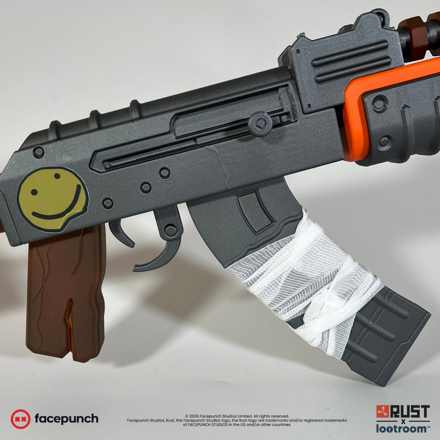 Close-up of the Rust AK prop receiver with the hand-painted yellow smiley and the bandage wrapped around the magazine