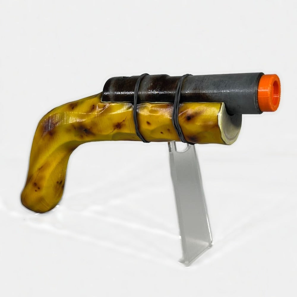 Rust Banana Eoka prop on the optional acrylic stand, banana grip with brown ripening spots and a near-black pipe barrel