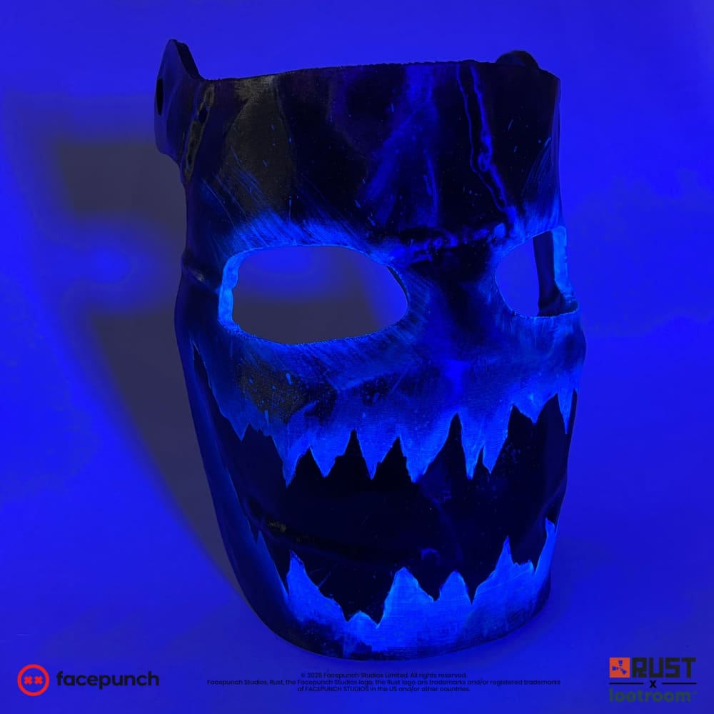 Rust Frostbite facemask prop glowing under blacklight at an angle, the jagged mouth standing out
