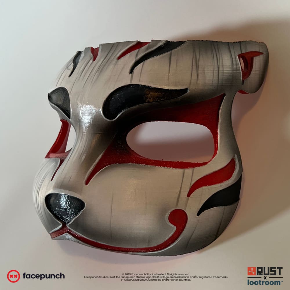 Rust Mendo kitsune facemask prop at an angle, showing the pointed ear and red edge outlines