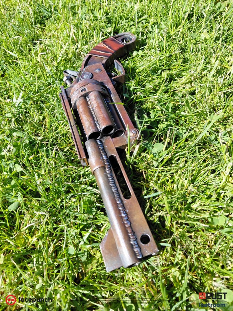 Rust High Caliber Revolver prop lying in grass, seen from above with the open cylinder