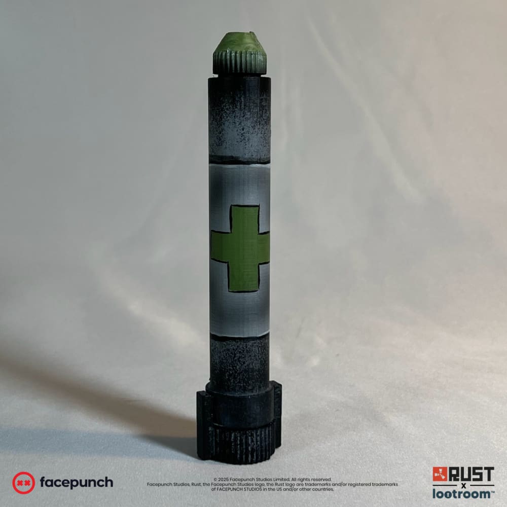 Rust Medpen prop standing upright, olive cross on the grey band and the ribbed green cap on top.