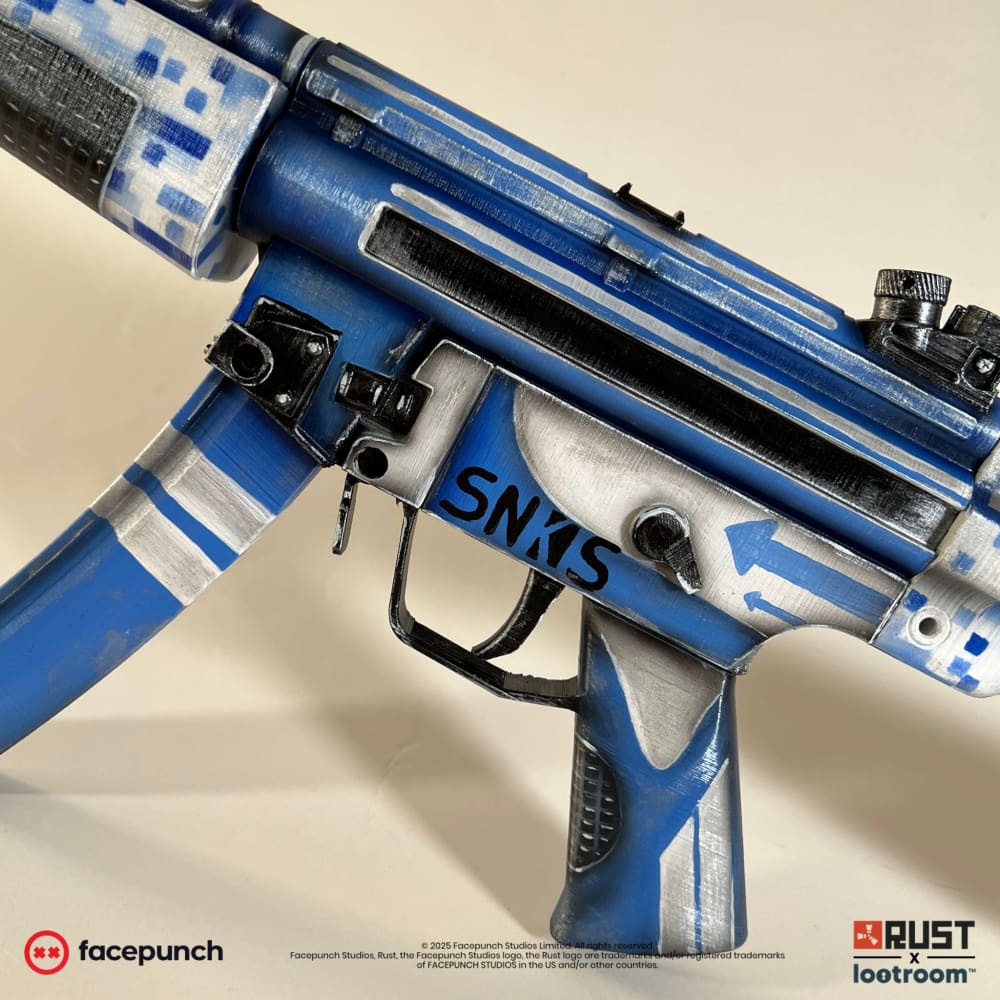 Close-up of the Rust Sinks MP5 prop's receiver with the SNKS lettering in black and the blue arrows.