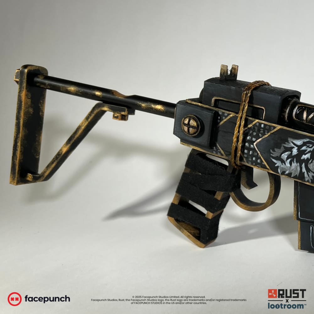 The Rust Anthric SAR prop at an angle, showing the stock, the gold cross boss and the real black strap around the grip.