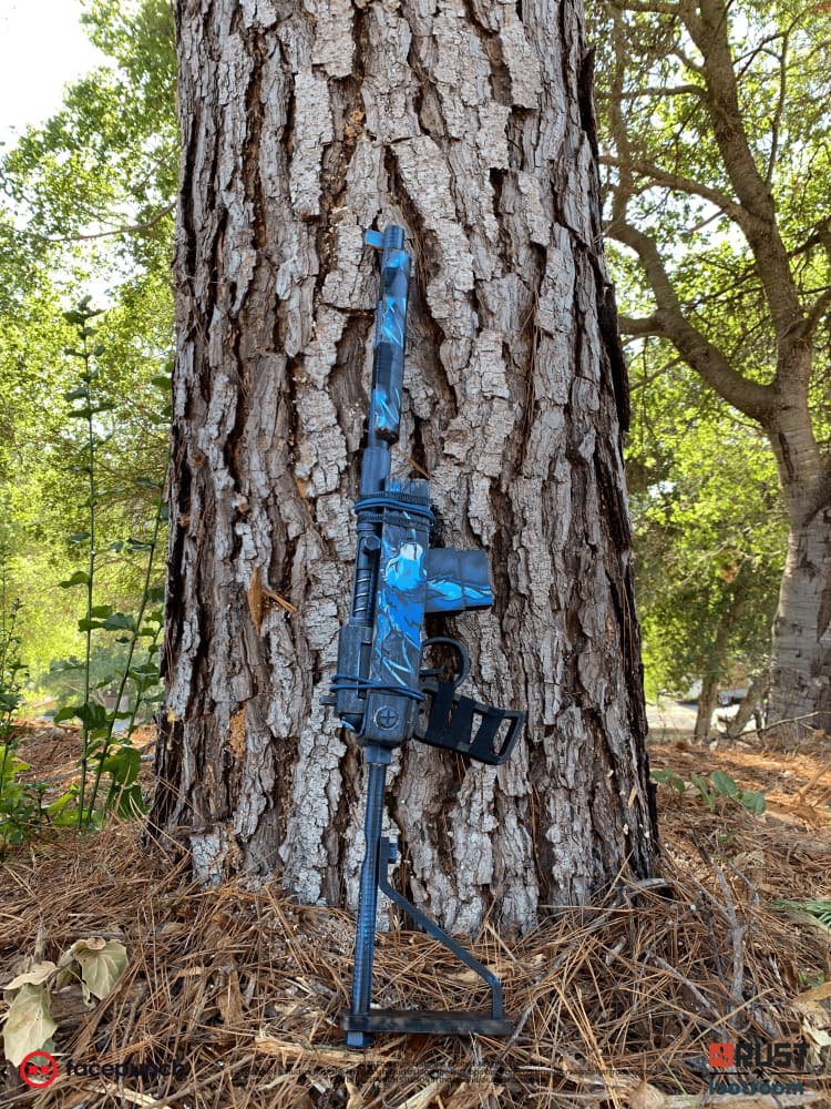 The Rust Blooprint SAR prop standing against a pine trunk, its full 75cm length upright.