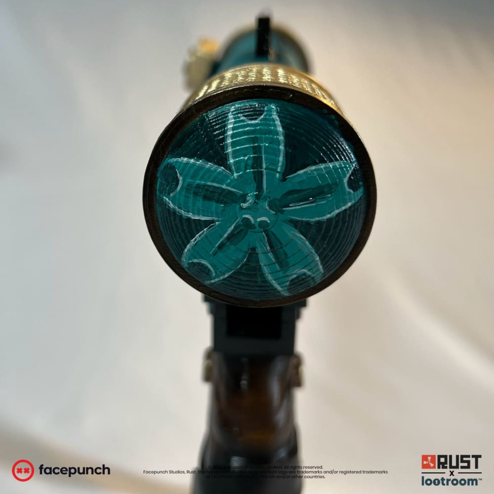 Head-on view of the Rust BeccaSomething SMG prop's gold rear cap, with the teal blossom painted on its face.