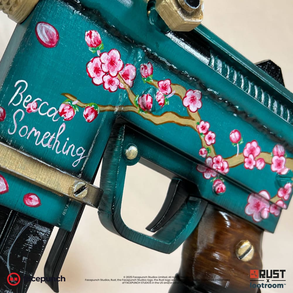 Close-up of the Rust BeccaSomething SMG prop's receiver, the blossom branch and the name written by hand in white.