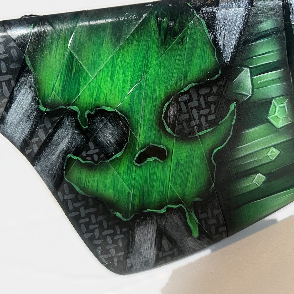 Close-up of the green skull on the stock of the Rust Oilrats Waterpipe Shotgun prop, on a diamond-plate textured panel.
